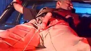 Officer Derek da Silva bound to the hood of a car