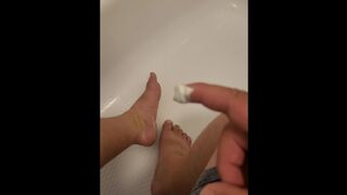 Chubby guy washes and lotions feet in bathtub
