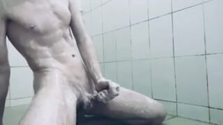 A young guy with a big dick shaves and masturbates in a public shower