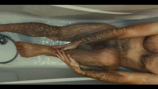 Hairy guy soaps up in bath, strokes, plays with his dick and foreskin and pisses on himself
